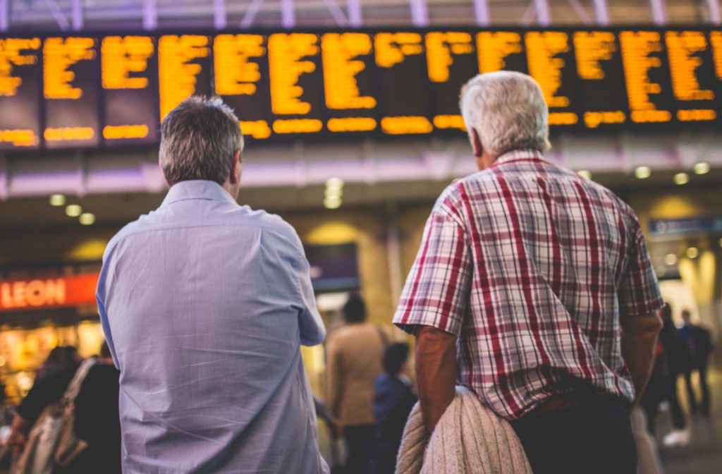 Chatbot transportation services ease commuter stress? Image: two commuters viewing large travel schedule. 